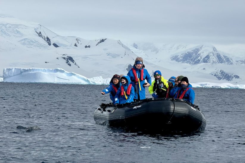 Zodiac navegando con turistas hacia desembarco Antártida límite IAATO 100.